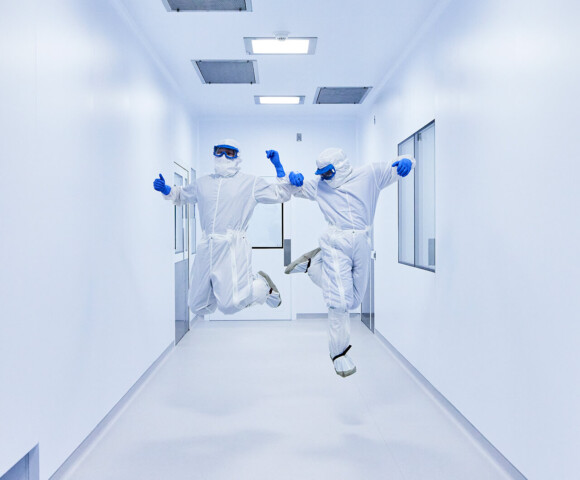 Two people in clean suits jumping in the air